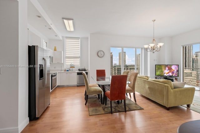 dining area with a healthy amount of sunlight, an inviting chandelier, and light hardwood / wood-style flooring