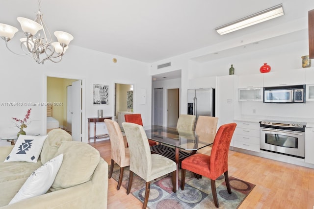 dining room with light hardwood / wood-style floors and an inviting chandelier