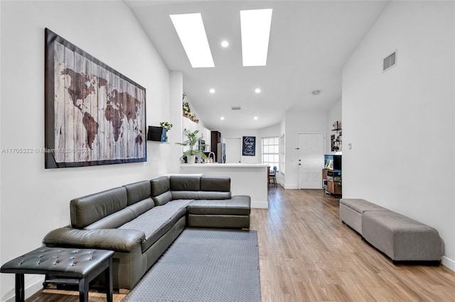 living room with light wood-type flooring and vaulted ceiling with skylight