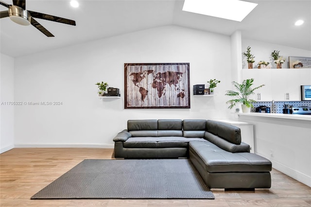 living room featuring ceiling fan, vaulted ceiling with skylight, and light hardwood / wood-style flooring