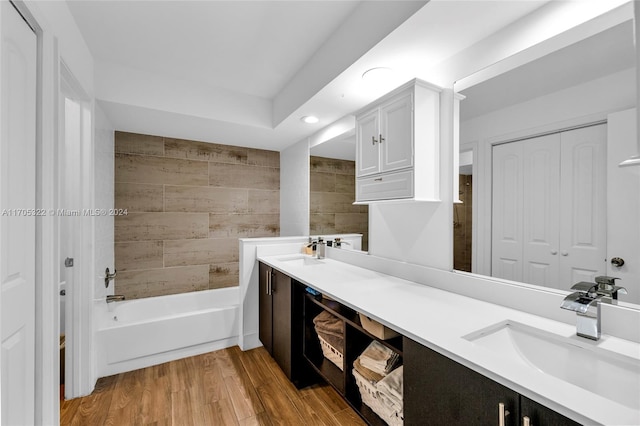 bathroom with hardwood / wood-style flooring, vanity, and tiled shower / bath combo