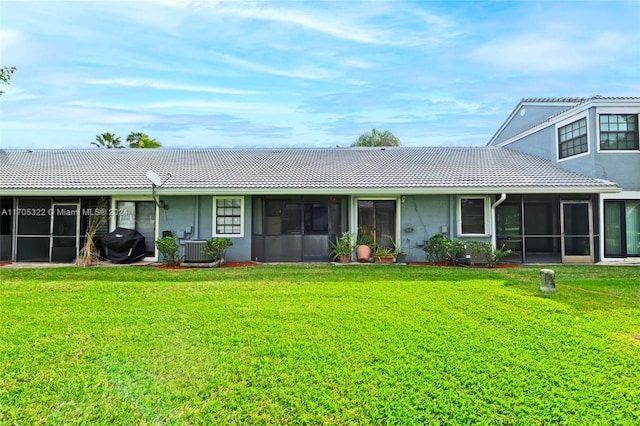 back of property featuring a sunroom, a lawn, and central AC