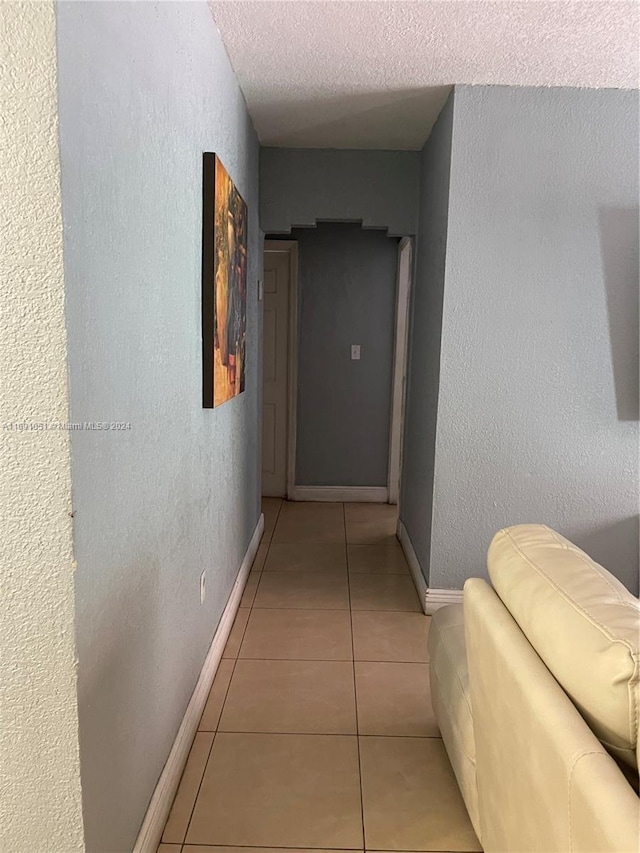 corridor featuring light tile patterned floors and a textured ceiling