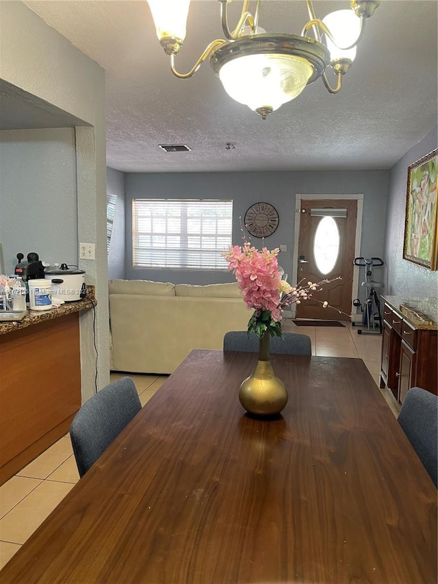 tiled dining area with a textured ceiling and a notable chandelier