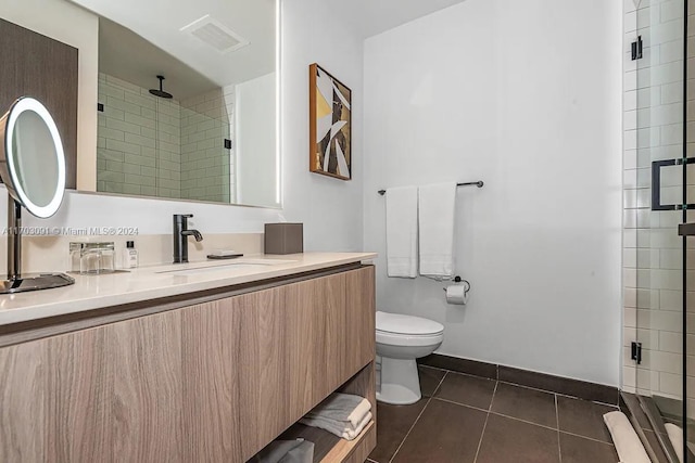 bathroom with tile patterned floors, a shower with door, vanity, and toilet