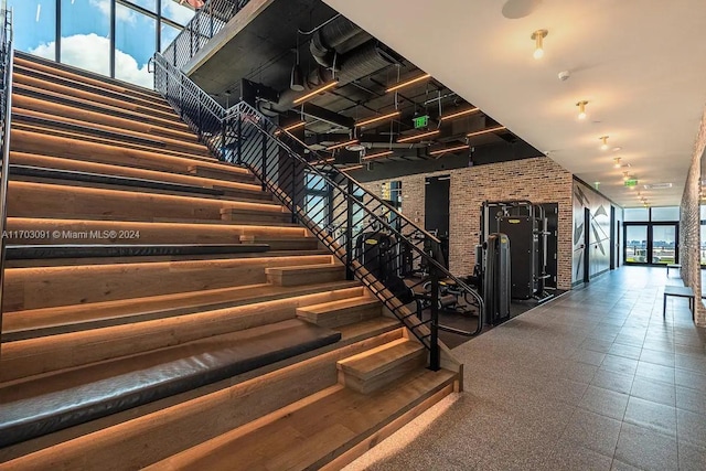 stairs with plenty of natural light and brick wall