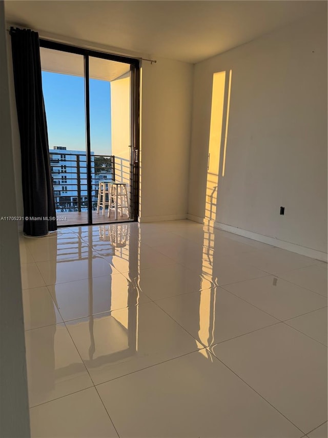 spare room with tile patterned floors and a wall of windows