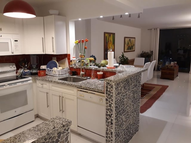 kitchen with light stone countertops, tasteful backsplash, white appliances, sink, and white cabinets