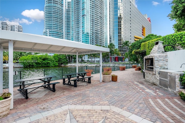 view of patio with a water view and an outdoor fireplace