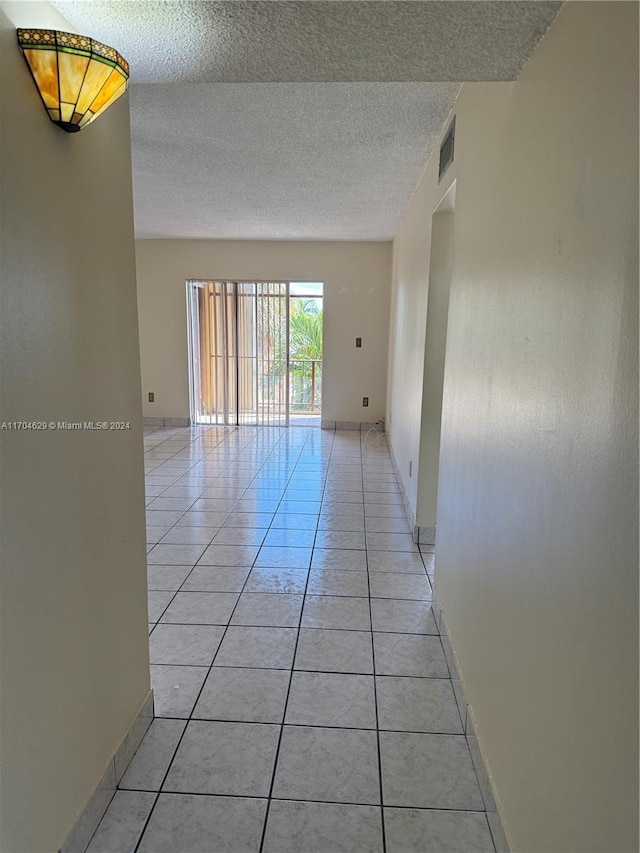 empty room with light tile patterned floors and a textured ceiling