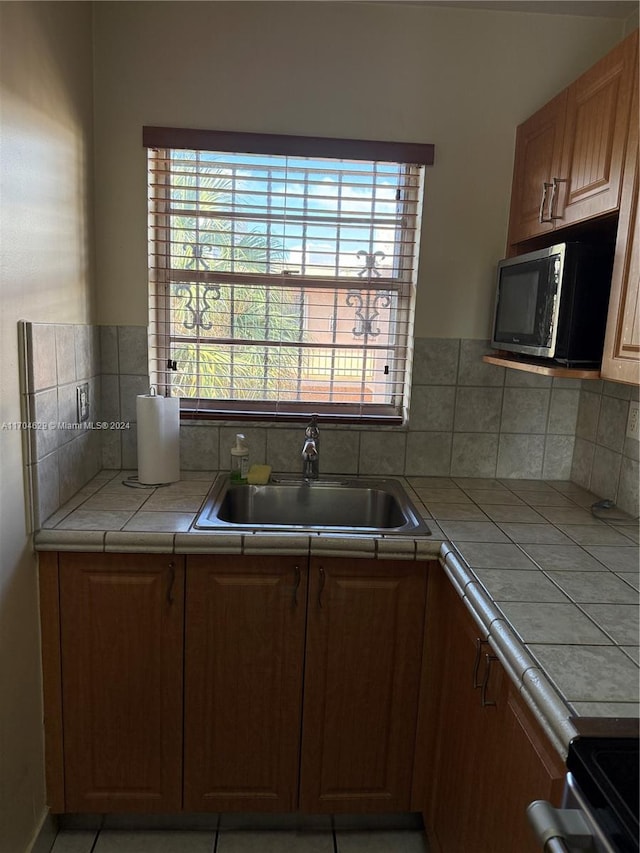 kitchen with tile countertops, electric stove, sink, and tasteful backsplash