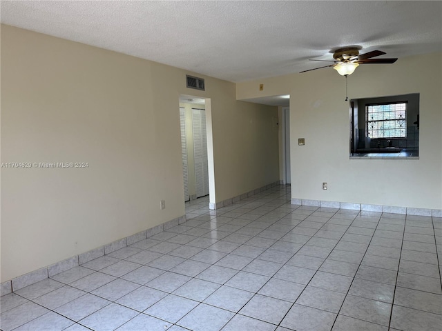 empty room featuring light tile patterned floors, a textured ceiling, and ceiling fan