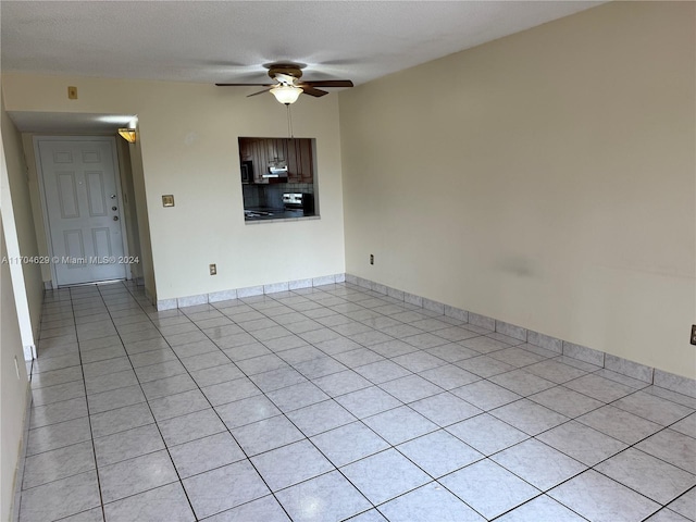 unfurnished room featuring ceiling fan, light tile patterned floors, and a textured ceiling