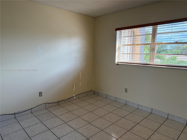 empty room with light tile patterned flooring and a textured ceiling