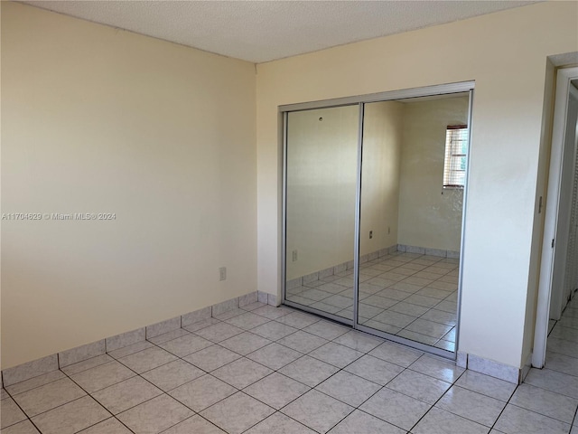 unfurnished bedroom with light tile patterned floors, a textured ceiling, and a closet