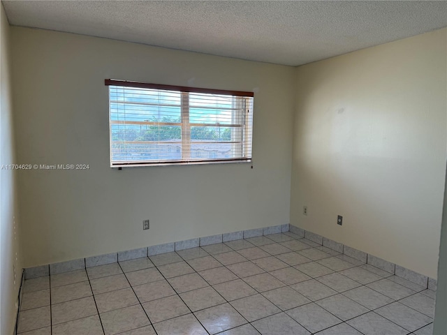 tiled empty room featuring a textured ceiling