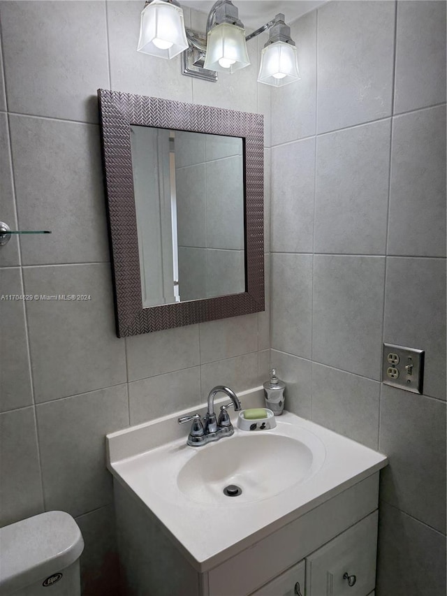 bathroom featuring decorative backsplash, vanity, tile walls, and toilet