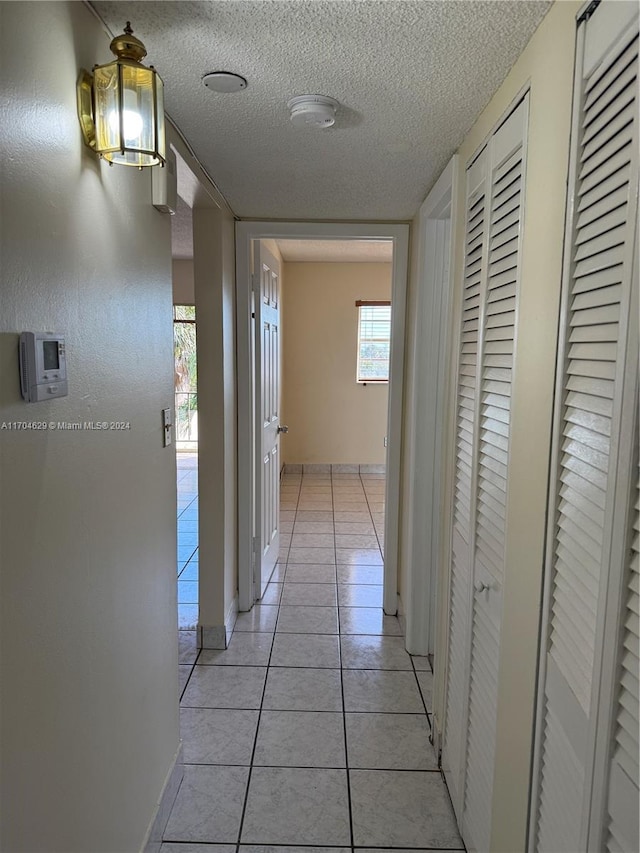 corridor featuring light tile patterned flooring and a textured ceiling