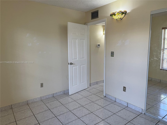 tiled empty room with a textured ceiling