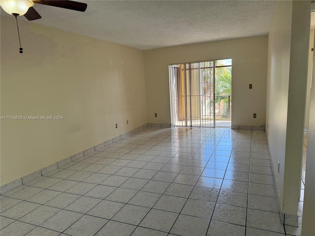 spare room featuring ceiling fan, light tile patterned flooring, and a textured ceiling