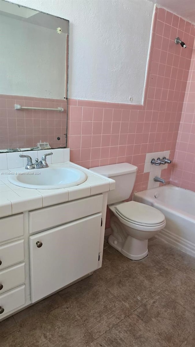 full bathroom with toilet, vanity, tiled shower / bath combo, and tile walls