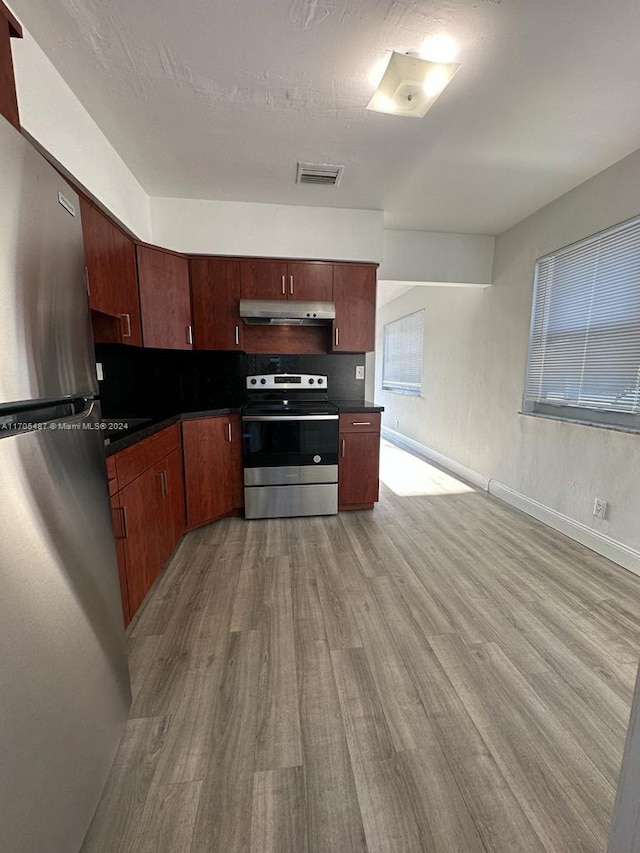 kitchen featuring backsplash, light wood-type flooring, and appliances with stainless steel finishes