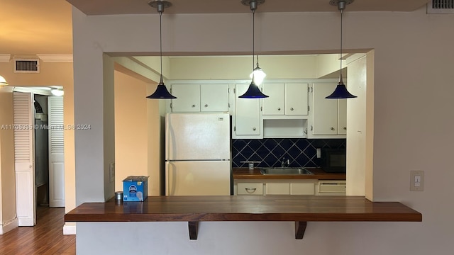 kitchen featuring pendant lighting, sink, ornamental molding, white fridge, and dark hardwood / wood-style flooring