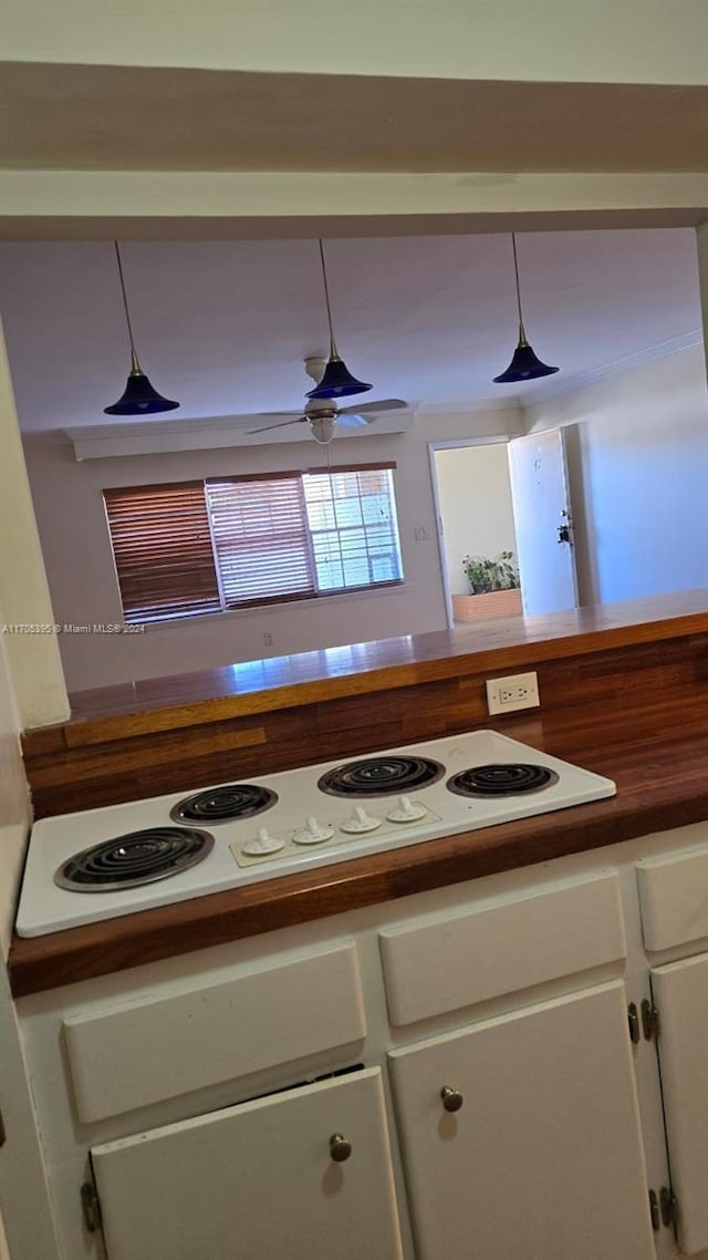 kitchen featuring white electric stovetop, ceiling fan, white cabinets, and pendant lighting