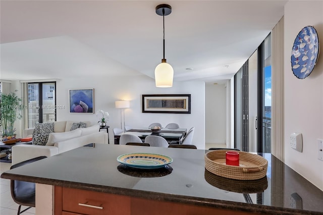 kitchen with a breakfast bar area, expansive windows, light tile patterned flooring, and decorative light fixtures