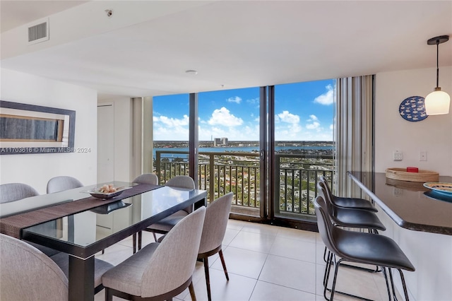 tiled dining area featuring a water view and a wall of windows