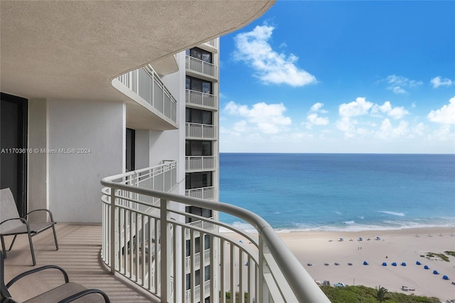 balcony with a water view and a view of the beach