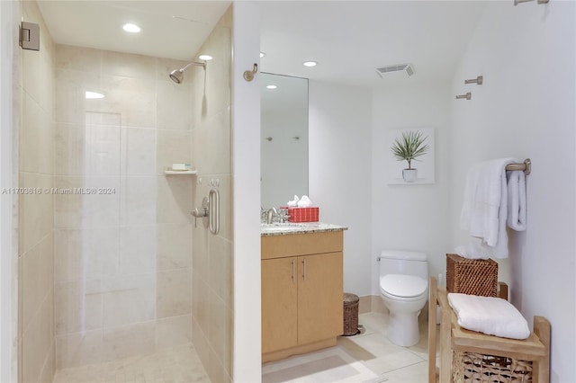 bathroom featuring tiled shower, vanity, toilet, and tile patterned flooring