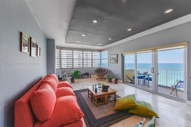 living room featuring a water view and a tray ceiling