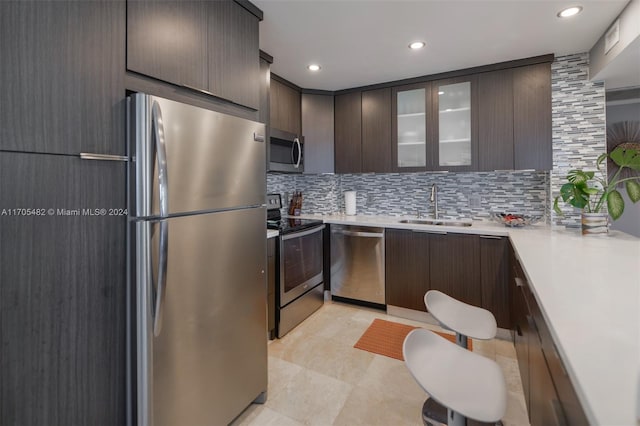 kitchen featuring dark brown cabinets, sink, backsplash, and appliances with stainless steel finishes