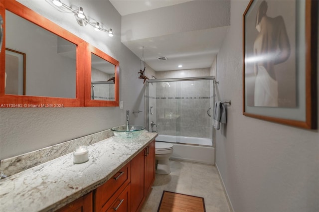 full bathroom with shower / bath combination with glass door, tile patterned flooring, vanity, and toilet