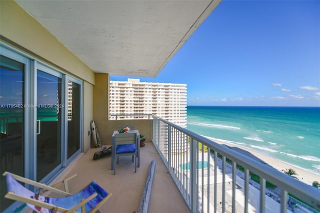 balcony with a water view and a view of the beach