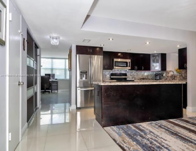 kitchen with appliances with stainless steel finishes, light tile patterned floors, and dark brown cabinets