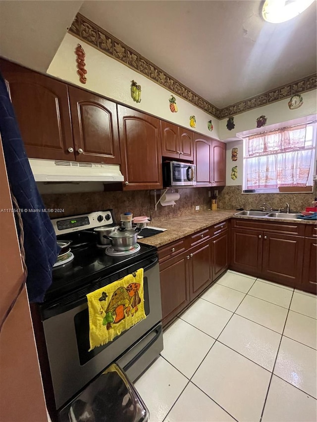 kitchen featuring appliances with stainless steel finishes, tasteful backsplash, light tile patterned floors, and sink