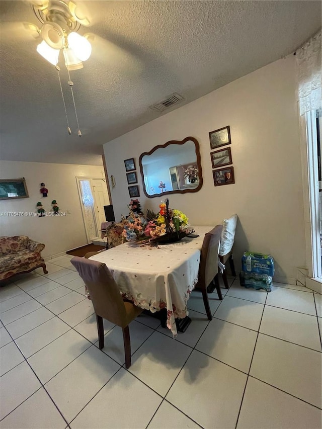 dining area with ceiling fan, light tile patterned flooring, and a textured ceiling