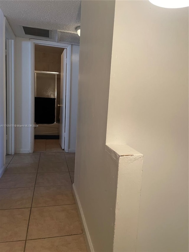 hall featuring a textured ceiling and light tile patterned flooring