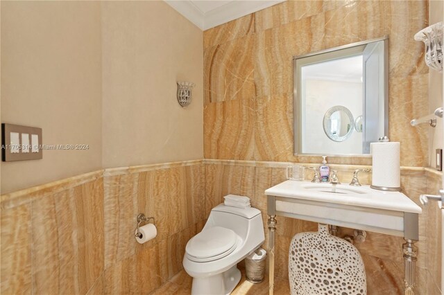 bathroom with sink, tile patterned floors, crown molding, toilet, and tile walls