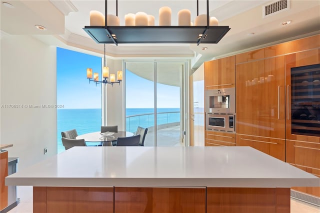 kitchen with crown molding, a water view, hanging light fixtures, and stainless steel microwave