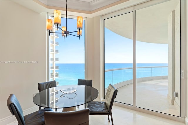 dining area with a water view, an inviting chandelier, and crown molding