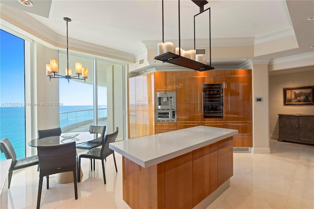 kitchen with ornamental molding, a water view, a chandelier, a kitchen island, and hanging light fixtures