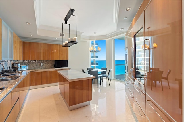 kitchen with a center island, sink, an inviting chandelier, backsplash, and pendant lighting