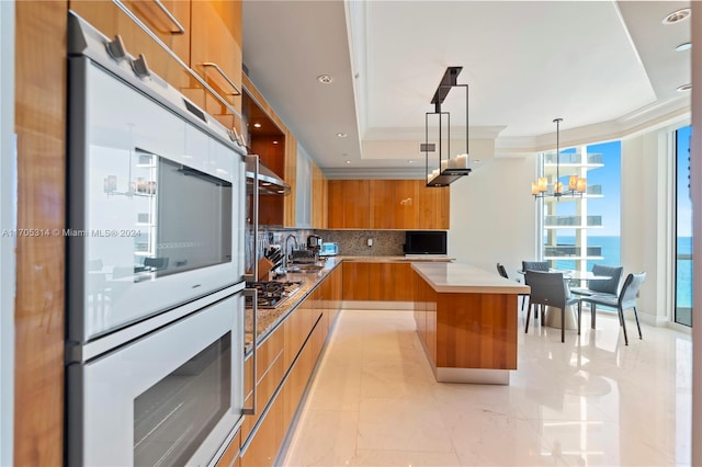 kitchen with decorative backsplash, ventilation hood, stainless steel appliances, decorative light fixtures, and a chandelier