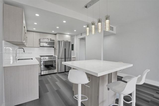 kitchen featuring sink, stainless steel appliances, a kitchen breakfast bar, dark hardwood / wood-style flooring, and pendant lighting