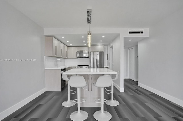 kitchen with sink, hanging light fixtures, stainless steel appliances, dark hardwood / wood-style floors, and a kitchen island