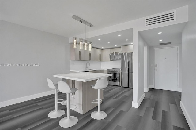 kitchen with a center island, dark wood-type flooring, sink, hanging light fixtures, and appliances with stainless steel finishes