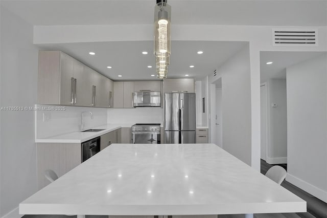 kitchen with pendant lighting, a center island, sink, and appliances with stainless steel finishes